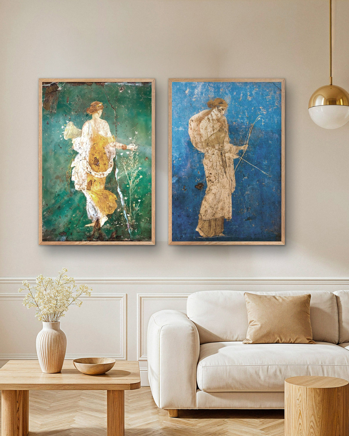 Set med 2 posters med romerska fresker, Flora och Artemis, i naturfärgade träramar ovanför en soffa i ett vardagsrum